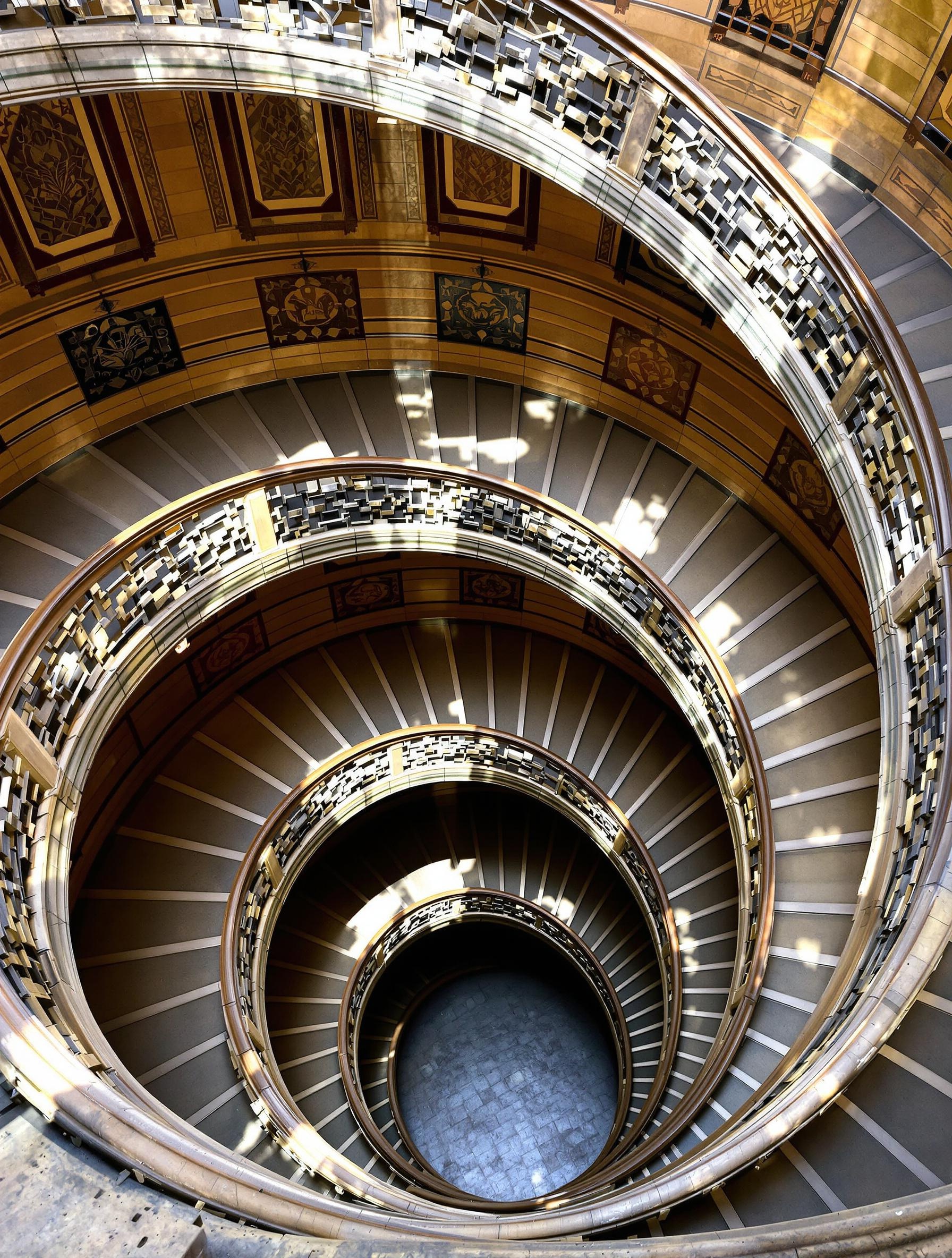 Photo en plongée épique sur l’escalier monumental en pierre de la Cour des Voraces à Lyon, six étages vertigineux, angle plongeant urban-style.