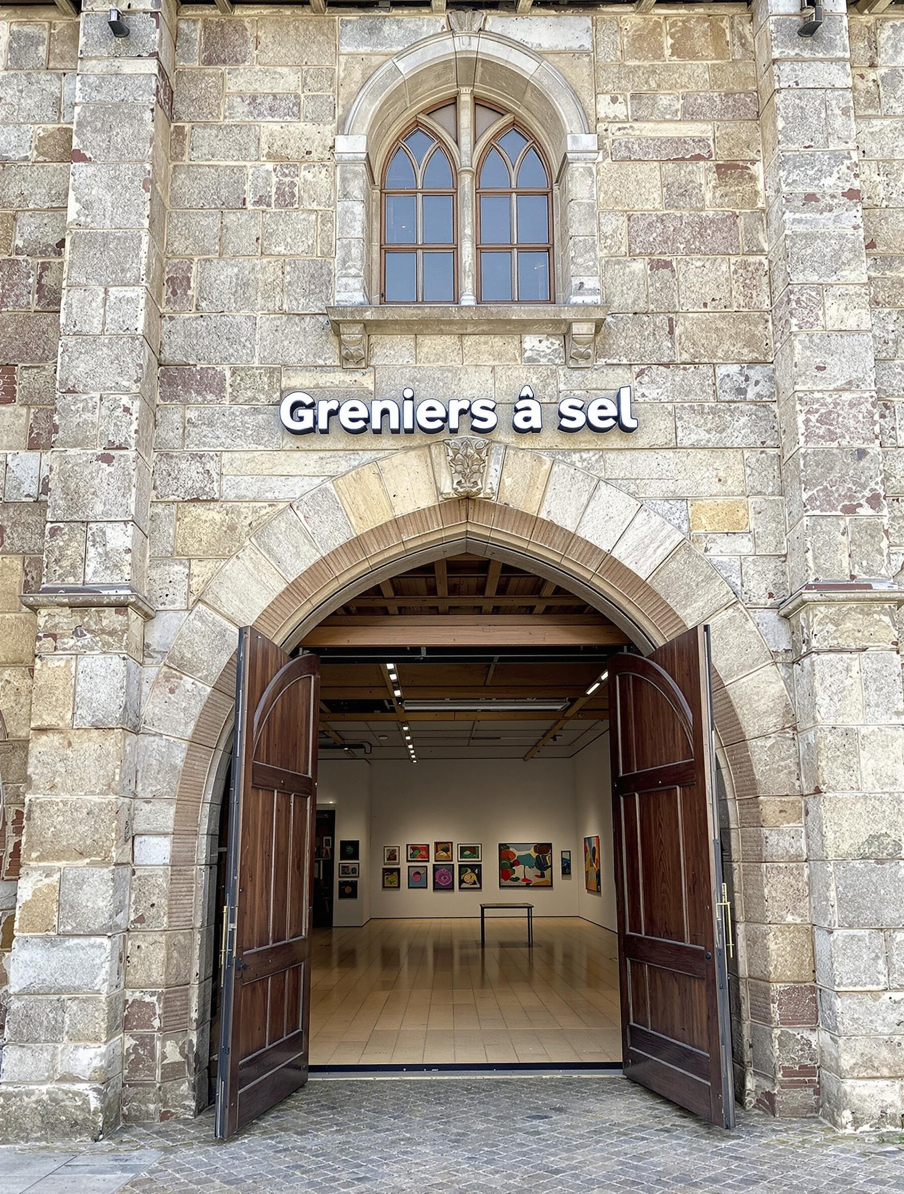 Façade massive des Greniers à sel à Honfleur avec exposition artistique visible