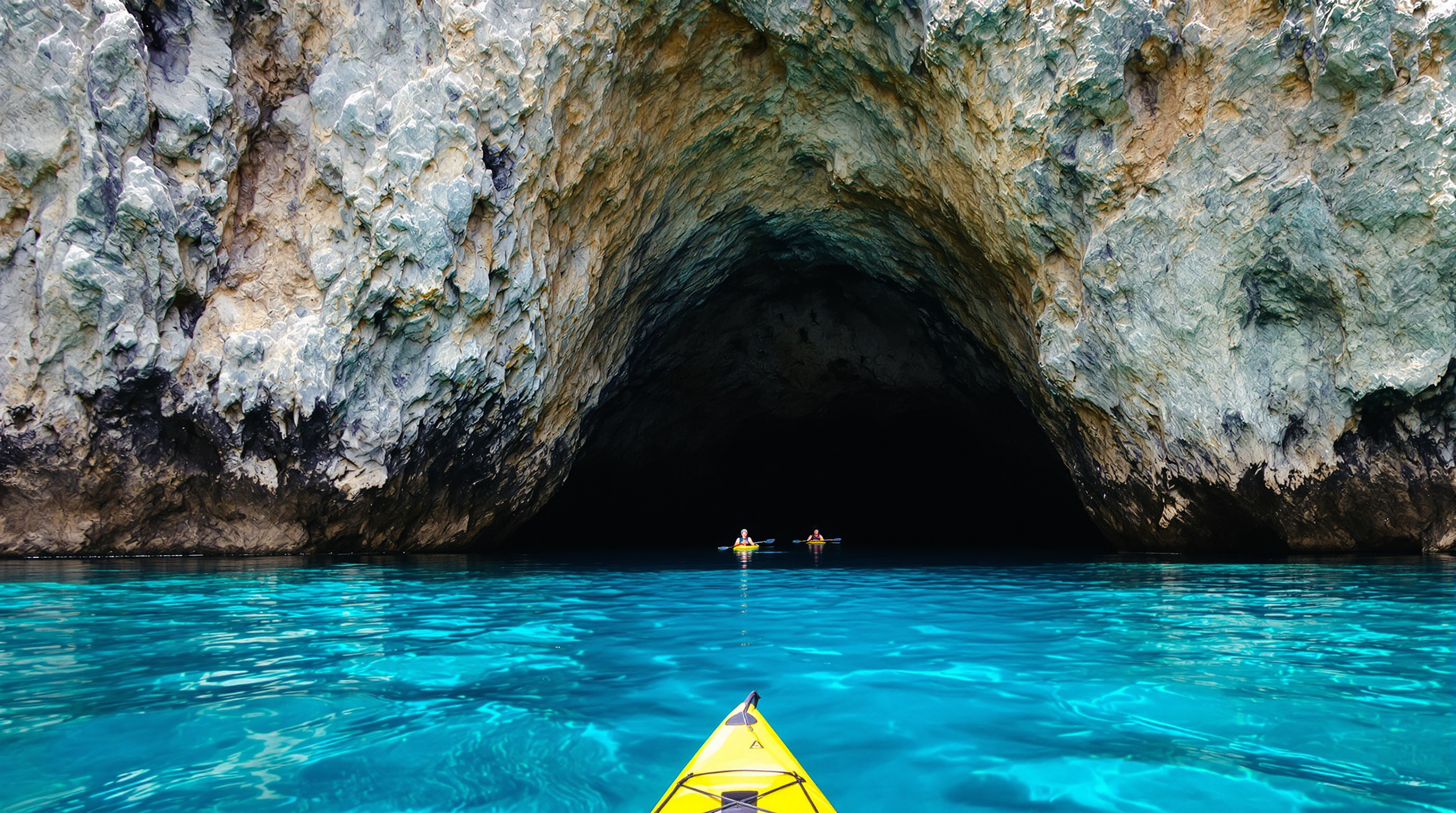 Kayak entrant dans la Cova Tallada depuis la mer turquoise